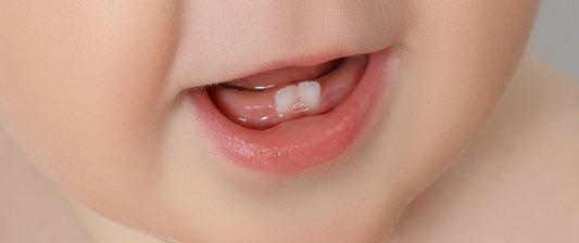 Un primo piano della bocca di un neonato che mostra i suoi primi dentini, segno dell'inizio della dentizione.