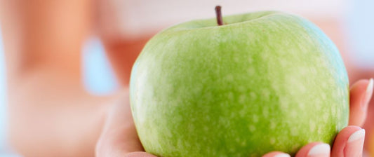 Una mano tiene una mela verde lucida in primo piano, mostrando un'immagine nitida e luminosa di un frutto fresco e sano.