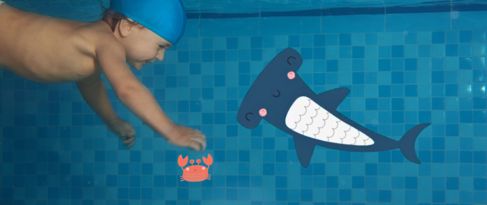 Un bambino nuota sott'acqua con una cuffia blu, circondato da illustrazioni colorate di un pesce martello sorridente e un piccolo granchio rosso, in un ambiente giocoso.