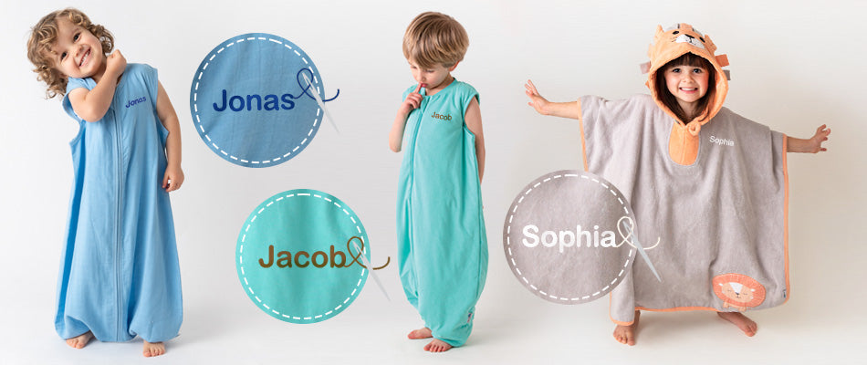 Tre bambini sorridono indossando sacchi nanna personalizzati con i loro nomi, Jonas, Jacob e Sophia. Uno di loro indossa un poncho con cappuccio a forma di leone.